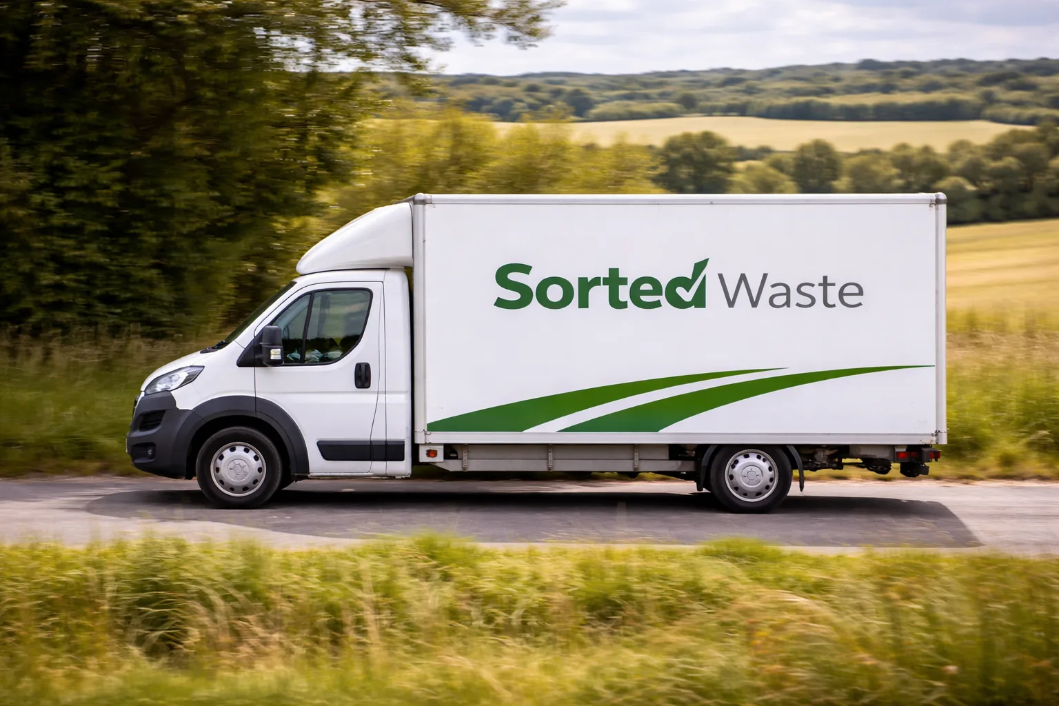 Waste clearance van on a country road with green fields